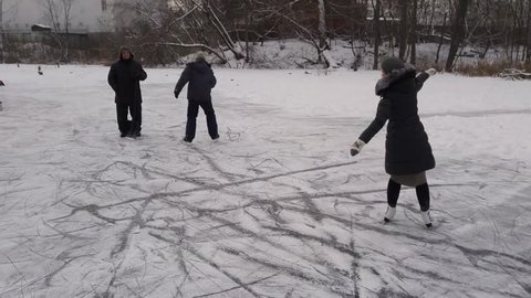 Family of seven with mother, boy and girl skate on ice of pond in park Losiny Ostrov, mobile phone video.