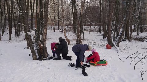 Boy and two girl dress ice skate on snow in wood near apartment building in park Losiny Ostrov, mobile phone video.