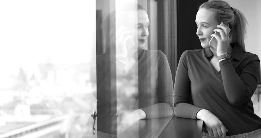 Elegant Woman Using Mobile Phone by window in office building