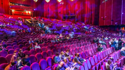 MOSCOW, RUSSIA - CIRCA JANUARY 2017: Spectators gather in the auditorium and watch the show in theatre timelapse. Large hall with red armchairs seats. Viewers filling places until turn off the light