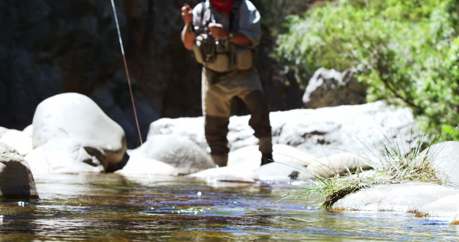 Fisherman fly fishing in river on a sunny day