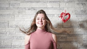 Cinemagraph Beautiful Brunette Woman standing against wall background with swaying heart.