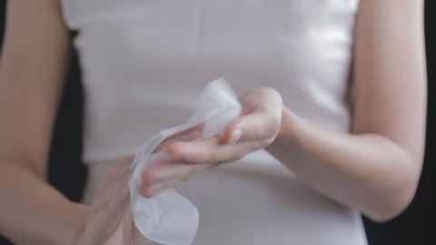 An Asian woman wiping hands with cleanliness wet tissue towel.