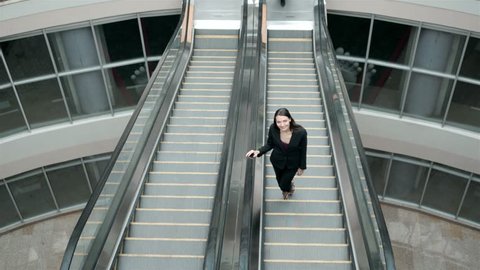 Business woman on escalator full lenght in shopping mall or office building or airport terminal.