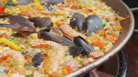 Spanish paella with yellow rice, shrimps and mussels cooking at the food market. Street food festival. Rice with seafood boiling close up. Traditional spanish food.