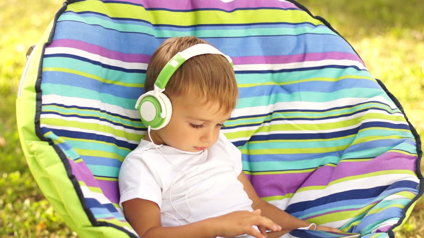 Smiling boy in headphones and playing with Tablet PC
