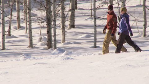 Couple walking through the snow with snow shoes on