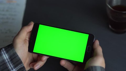 Watch video. Man holding a smartphone, hand of man holding mobile smart phone with chroma key green screen on white background, new technology concept