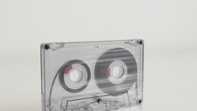 Close-up of retro analogue compact audio cassette 4K 2160p 30fps UltraHD footage - Transparent magnetic tape on white background 3840X2160 UHD tilting video