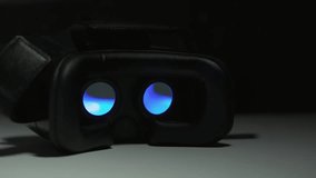 Movie playing inside virtual reality device at night indoor on white table and dark background. Black VR goggles. Modern technologies concept. 4k UHD video with interesting light effect