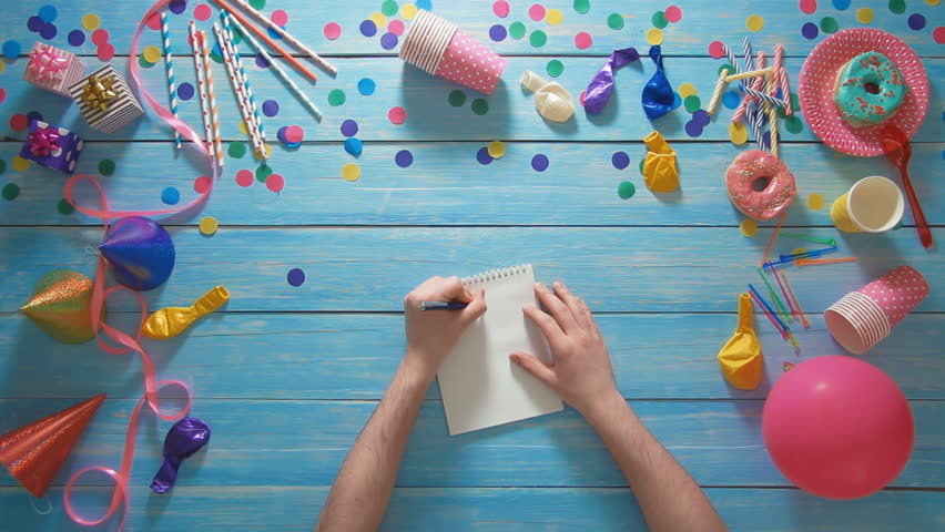 Top view man planning birthday party using paper notebook