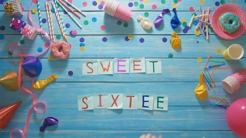 Top view man puts words Sweet Sixteen on the table with birthday decoration