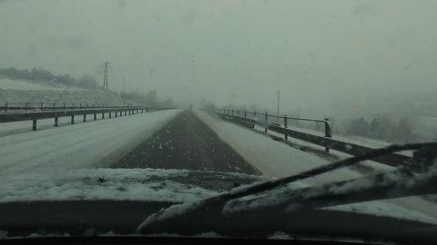 4-wheel car with studded winter tyre runs snow-covered Highway - Point of view, from inside moving vehicle.