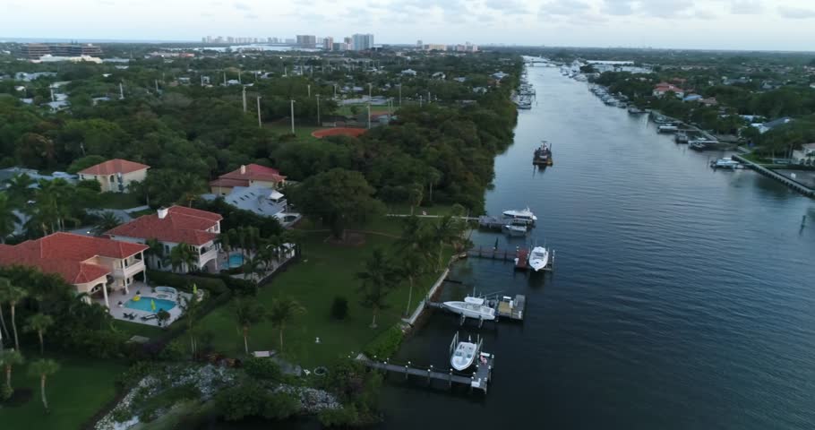 An aerial view follows Juno Beach waterfront homes, private docks, boats, and a tree-lined canal, 2017.