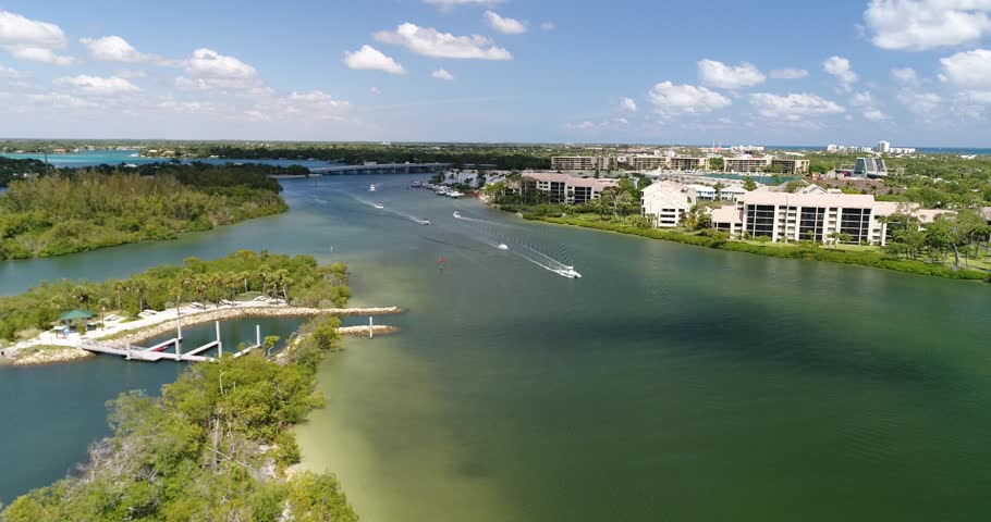 Wide aerial view across Jupiter waterfront condominiums, boats, docks, blue water, and a cloud-filled sky, 2017.