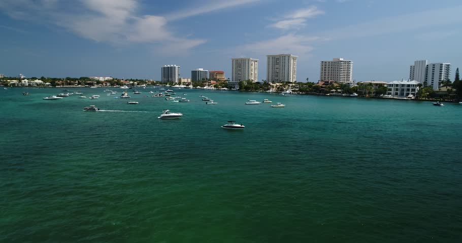 Aerial view circling a powerboat on Boca Raton water with condominium towers and moored boats behind, 2017.
