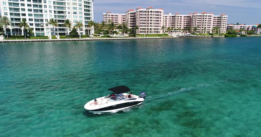 Aerial orbit around a speedboat on Boca Raton water with condominium towers lining the distant shore, 2017.