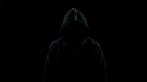 Portrait of invisible man with a hood nodding his head indoor on black background