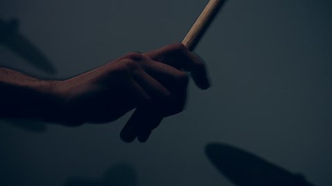Drummer plays drums kit. Drummer hand silhouette with drumstick. Close up of drummer hand playing drum plate on rock concert. Rock band performing on stage. Close up of drum plate