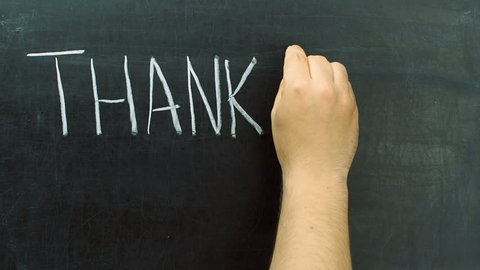 Hand writing thank you word with chalk at blackboard or chalkboard