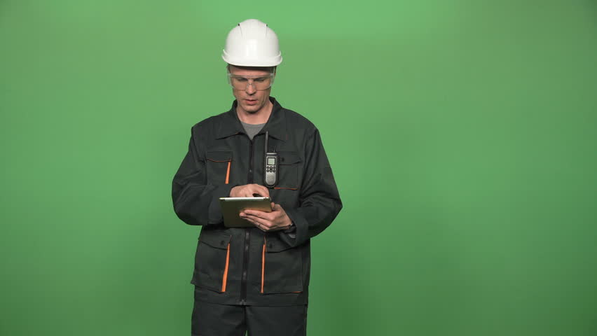 Engineer in protective suit with hard hat and digital tablet islated on green screen