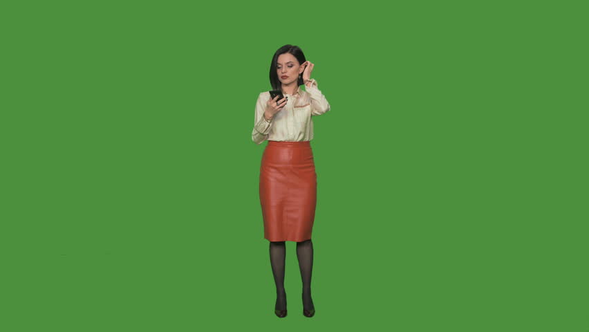 Young business woman in formal suit answering and talking phone isolated on green background.