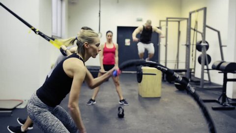 Young people in crossfit gym working out with various equipment.