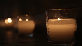 Many candles glowing in darkness of home interior.  Christmas or romantic dinner decor. Real time full hd video footage.