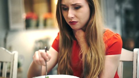 Girl looks worried while eating lunch in the cafe and having sore throat, steadycam shot
