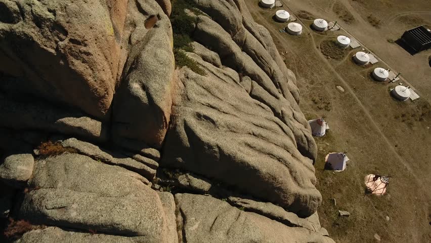 Park Terelj rocks and steppe near Ulaanbaatar Mongolia. Summer autumn sunny blue sky clouds. Beautiful Mongolian nature. Aerial drone flight above hotel tent yurt camp close to the mountain