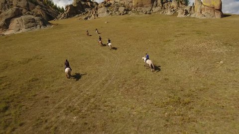 Park Terelj rocks and steppe near Ulaanbaatar Mongolia. Summer autumn sunny blue sky clouds. Beautiful Mongolian nature. Aerial drone helicopter flight follow nomads horseman riders
