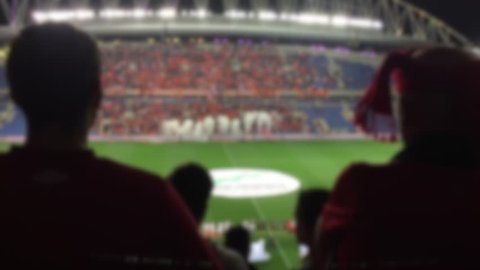 Soccer stadium with blurred unrecognizable fans in red
