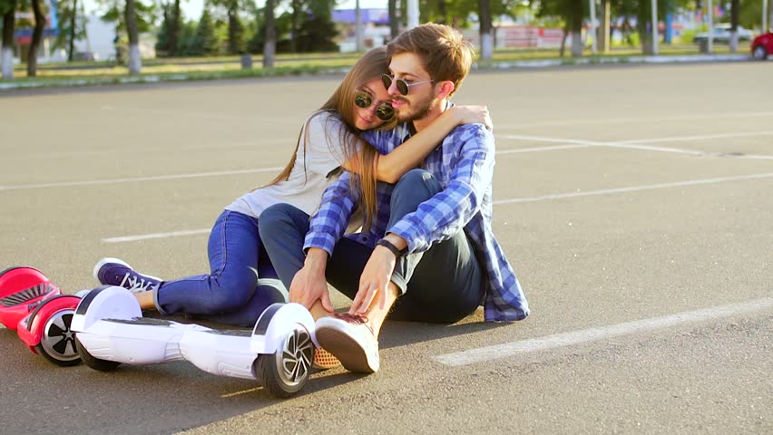 Couple with two hover boards relaxing and kissing