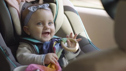 Cute Baby Girl Plays With Toy In Car Seat, She Smiles And Laughs, Ready To Go For A Ride In Family Car 