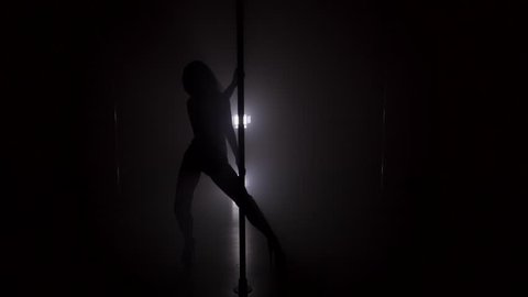 Silhouette of woman dancing near the pole in strip shoes