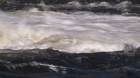 Water rushing fast and furious over hydroelectric power dam after storm.
