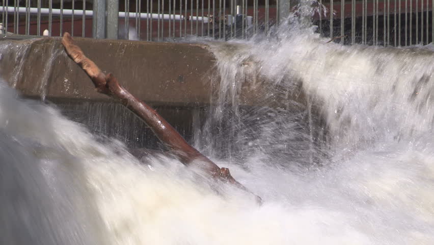 Water rushing fast and furious over hydroelectric power dam after storm.
