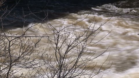 Massive waves and torrent of water rushing down river near dam and spillway