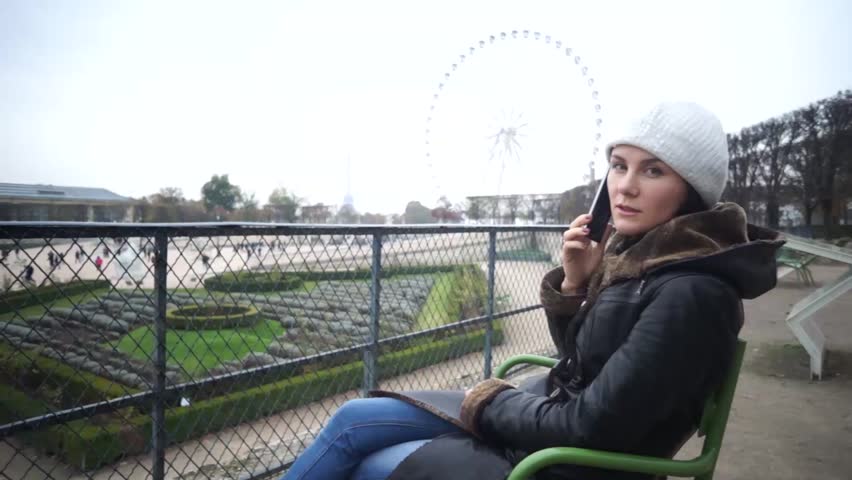 Cute girl with cellphone in Paris, France, near the Louvre.