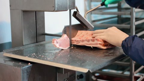 Freshly frozen steak meat is cut with a saw in the production. Ready-made steaks for cooking in a restaurant on fire and coals