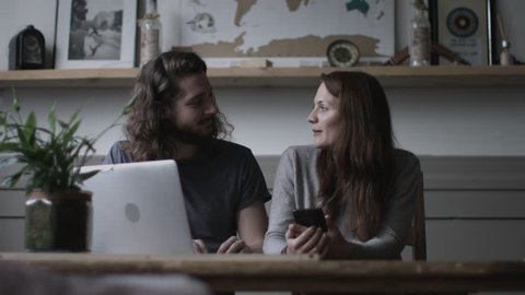 Young adult couple using a laptop and smartphone together