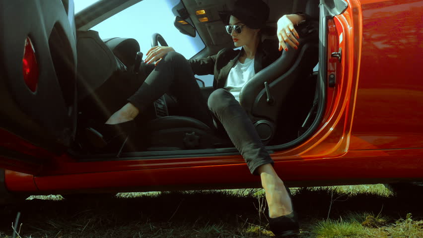 Sexual young stylish lady on high heels posing in red sport car