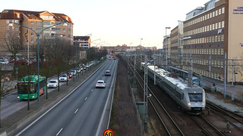 City street and railway track in Helsingborg, Sweden. Traffic and commuter train passing by