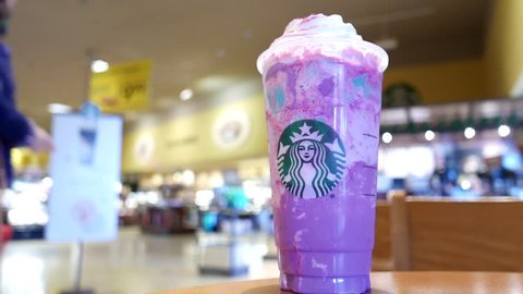 Coquitlam, BC, Canada - April 20, 2017 : Motion of people buying coffee inside Starbucks store with limited edition unicorn frappuccino blended beverage on table