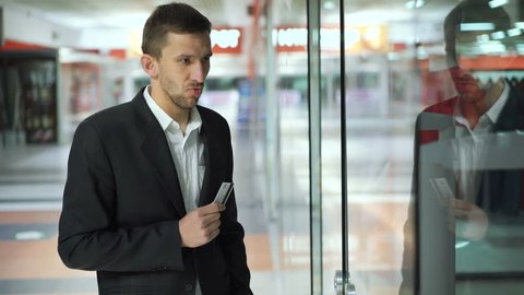Indecisive man doesn't know whether to buy dress for wife and looks on cards 4K