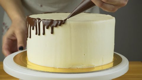 Chocolate icing on the cake. White cake covered with chocolate and cream. Chocolate cake decoration.
