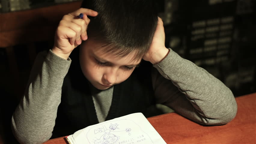 Tired schoolboy draws abstract animals in his notebook