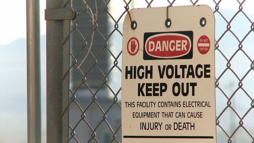 Danger Warning Sign on a fence with electrical industry in the background