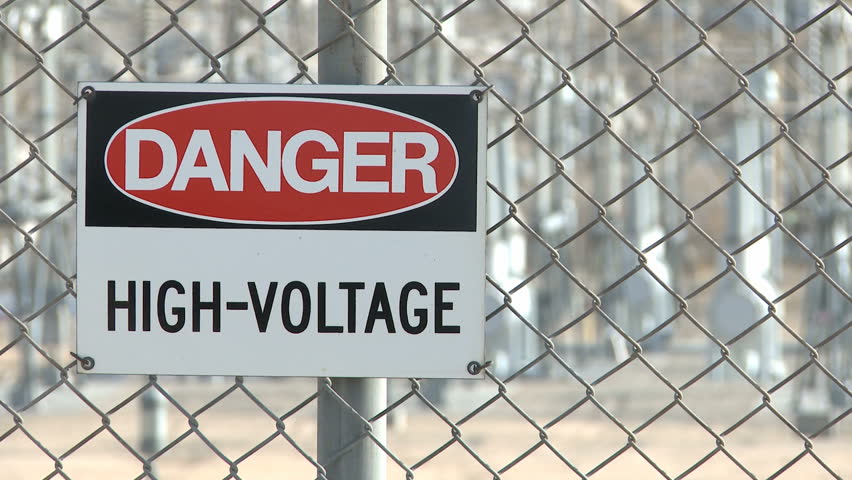 Danger Warning Sign on a fence with electrical industry in the background