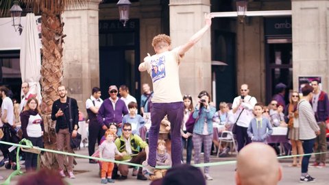 BARCELONA, SPAIN - APRIL, 16, 2017. Tightrope acrobat performing in the street. Balancing on a swaying strap. 4K video